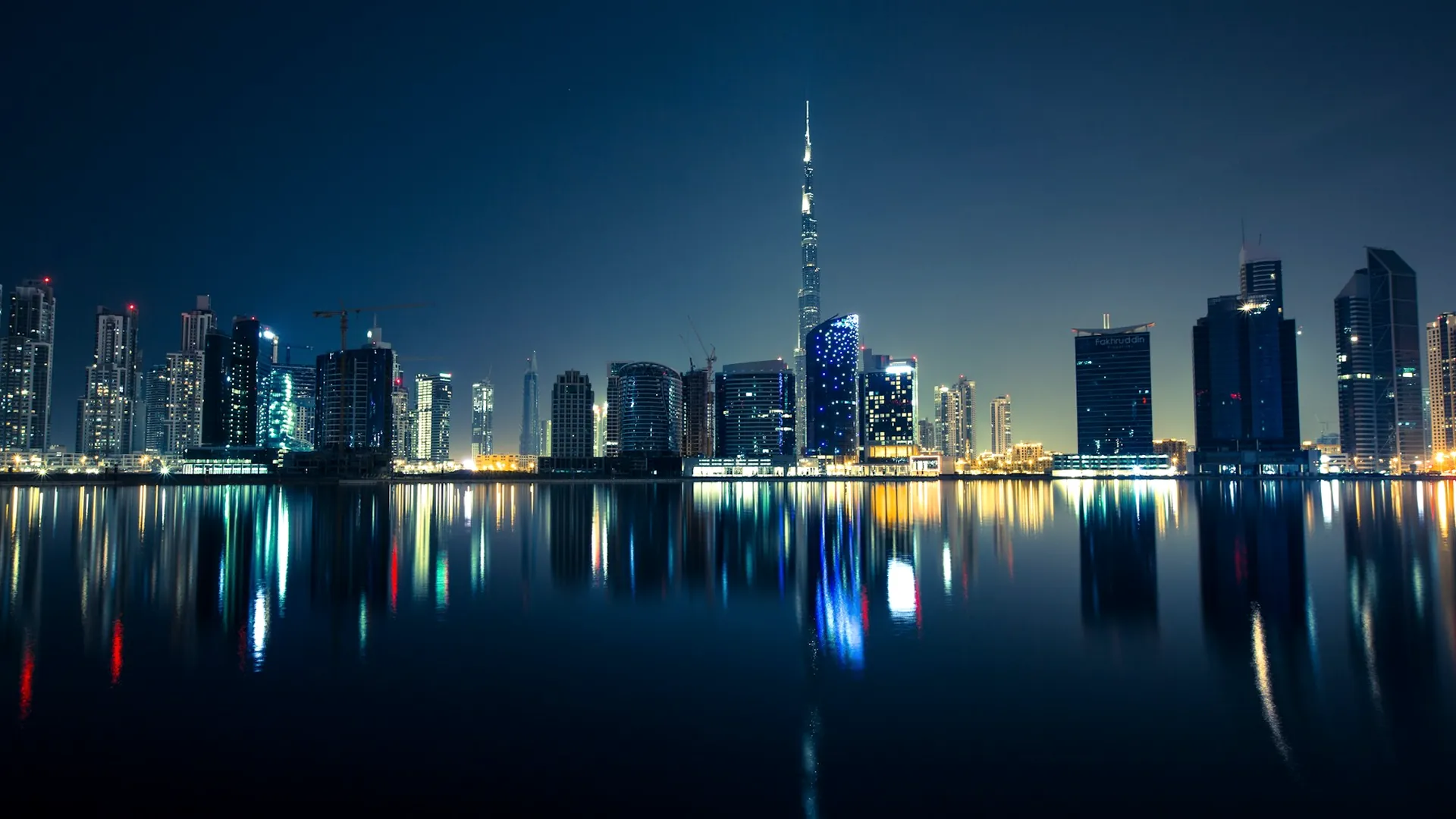The Dubai skyline reflected in still water at night