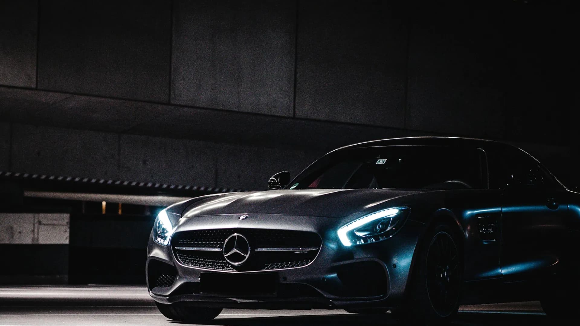 A dark luxury car lit from the side in an underground garage in Dubai